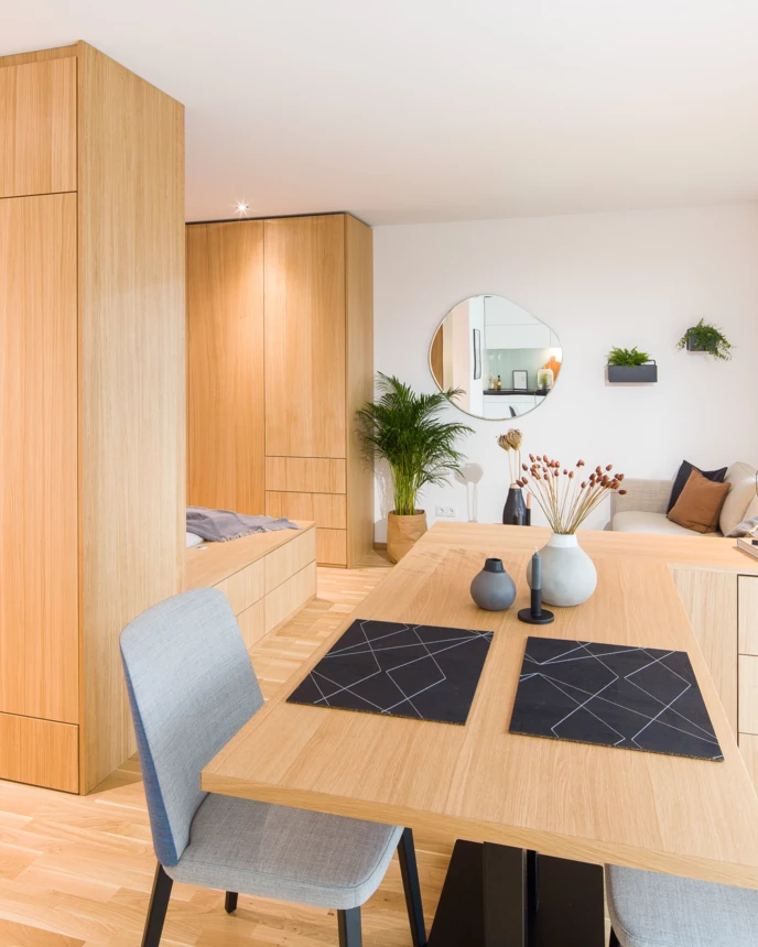 Modern eingerichteter Wohnraum "David" mit Esstisch und Stühlen, integrierten Holzmöbeln, Lounge-Bereich und einem Fenster (Couch, Bett).