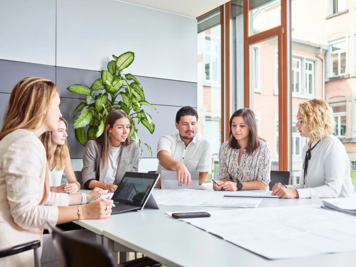 Mitarbeiter am Arbeitsplatz Büro Office Tablet Laptop Besprechung großer Tisch